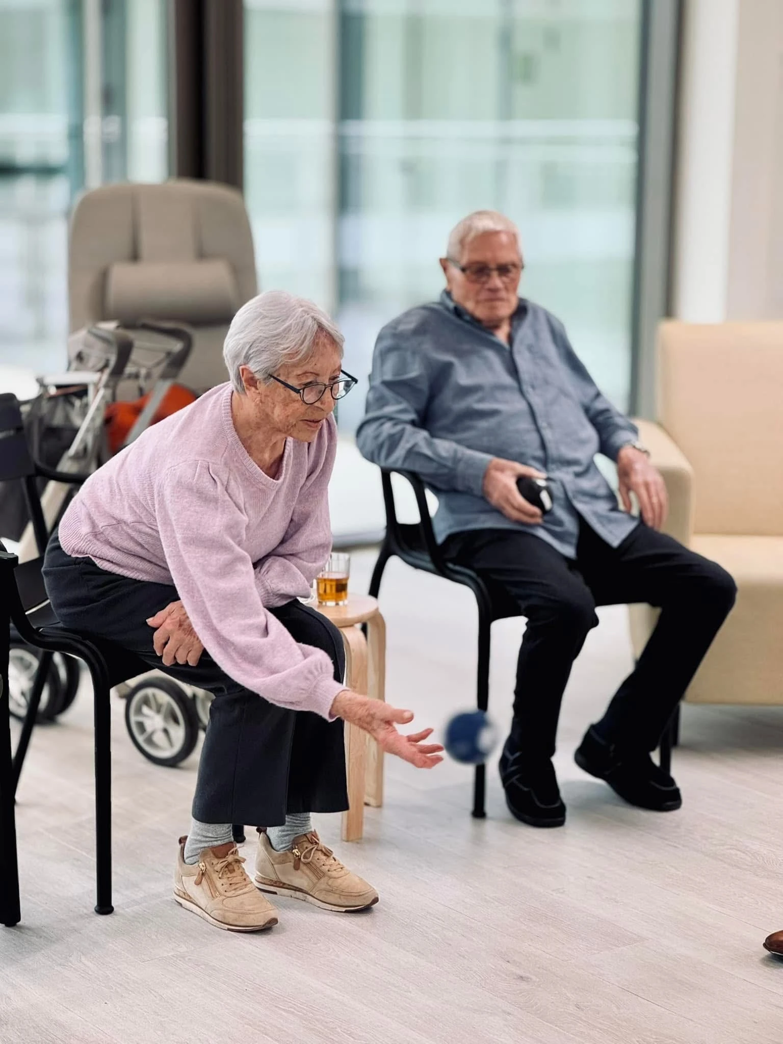 Vrouw en man zitten op stoel en smijten bal