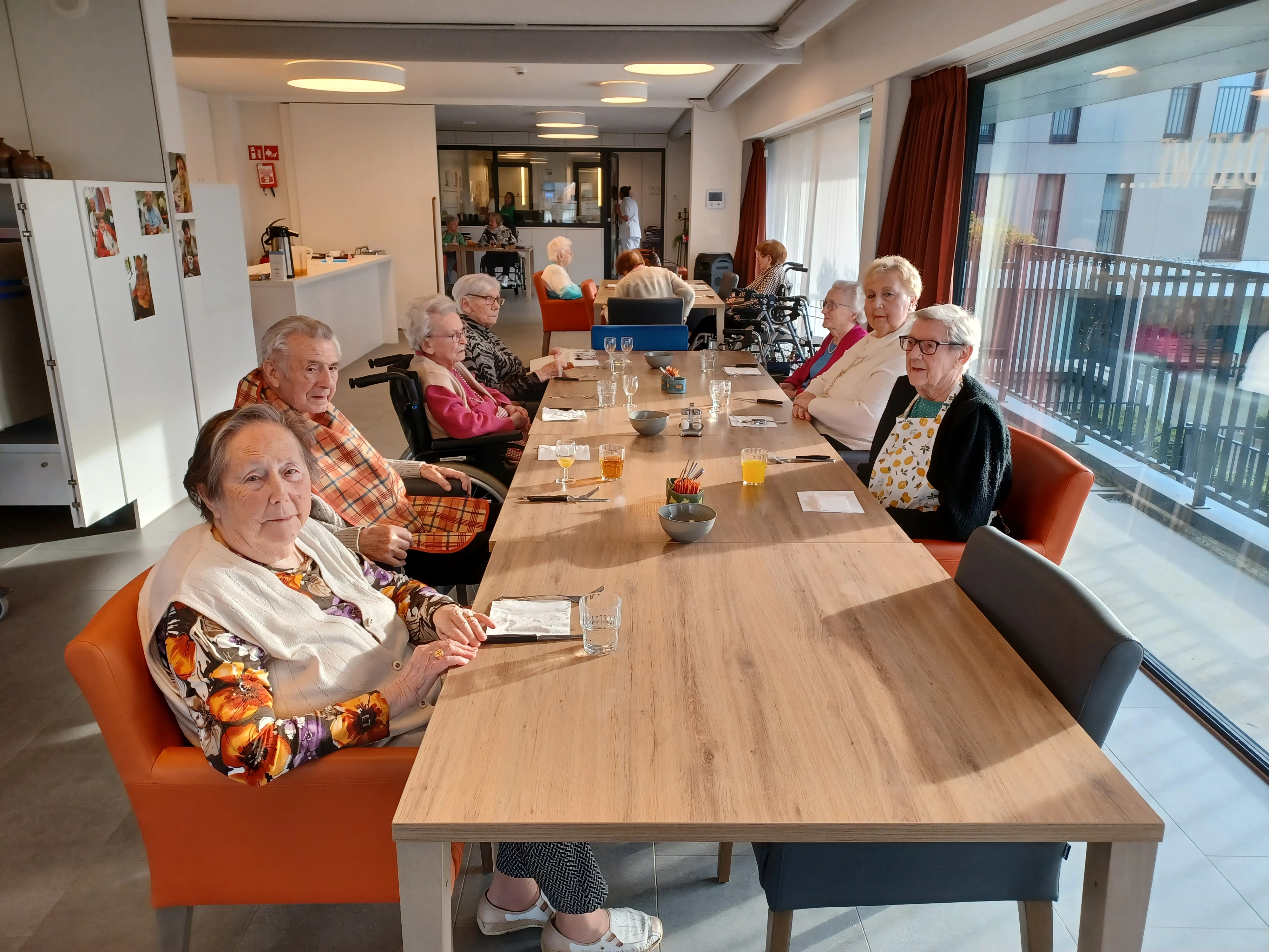 Bewoners zitten rond de tafel en drinken een glas